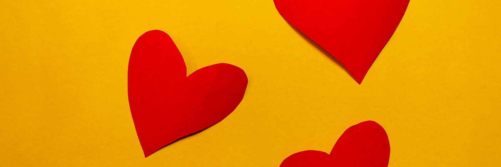 3 red paper hearts on a bright yellow background